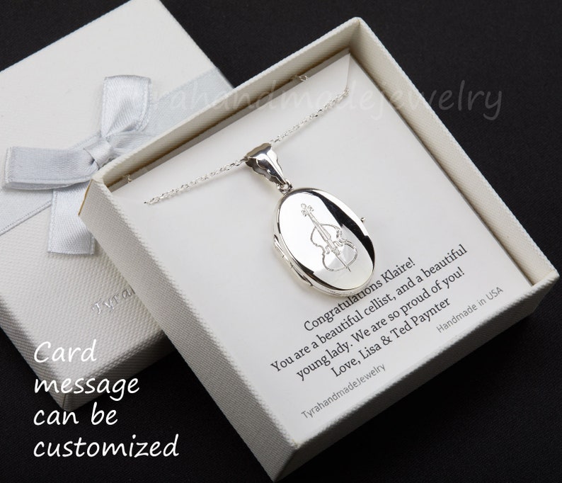 May include: A silver locket necklace with a cello engraving, presented in a white gift box with a silver ribbon. The box contains a personalized message. The locket is on a delicate chain.