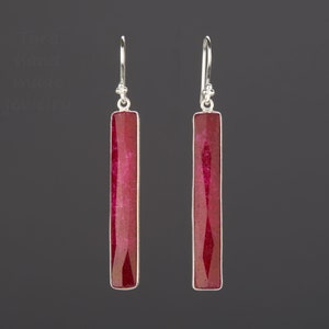 May include: A pair of silver earrings with long, rectangular red gemstone drops.
