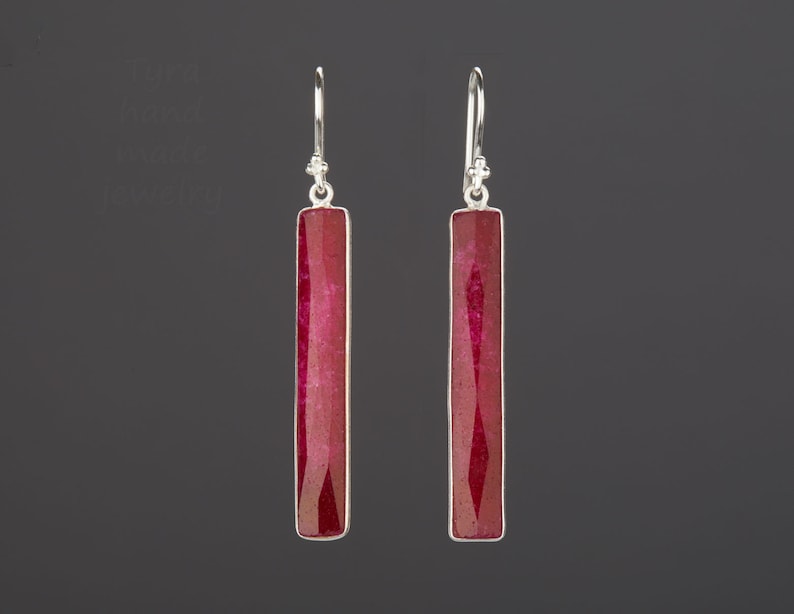 May include: A pair of silver earrings with long, rectangular red gemstone drops.