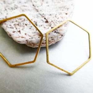 Peut inclure: Deux hexagones en m&eacute;tal de couleur laiton, fins et &agrave; cadre ouvert, avec une finition mate et lisse. Les formes g&eacute;om&eacute;triques sont constitu&eacute;es de fil m&eacute;tallique mince, formant chacune six c&ocirc;t&eacute;s &eacute;gaux, pr&eacute;sent&eacute;es comme des &eacute;l&eacute;ments s&eacute;par&eacute;s.
