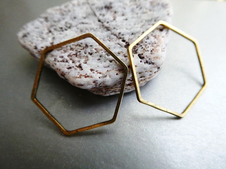 Peut inclure: Deux hexagones ouverts en laiton fin avec une finition mate. Les formes g&eacute;om&eacute;triques sont constitu&eacute;es de fil m&eacute;tallique mince et pr&eacute;sentent des coins angulaires nets. Le laiton a une teinte dor&eacute;e sourde et l&eacute;g&egrave;rement patin&eacute;e.