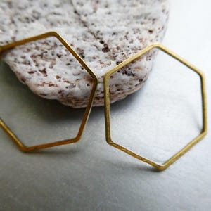 Peut inclure: Deux hexagones ouverts en laiton fin avec une finition mate. Ces formes g&eacute;om&eacute;triques sont constitu&eacute;es de fil m&eacute;tallique mince et pr&eacute;sentent un design hexagonal plat et coh&eacute;rent. Le laiton a une teinte dor&eacute;e mate et l&eacute;g&egrave;rement patin&eacute;e.