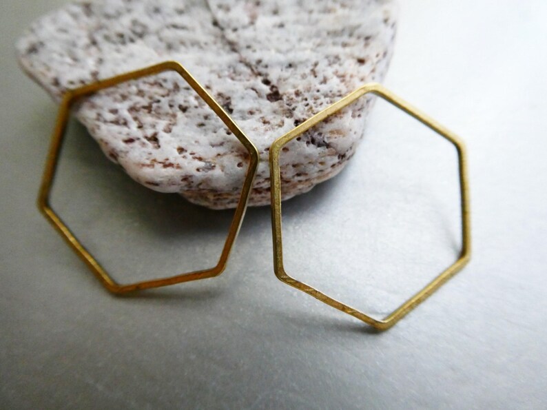 Peut inclure: Deux hexagones ouverts en laiton fin avec une finition mate. Ces formes g&eacute;om&eacute;triques sont constitu&eacute;es de fil m&eacute;tallique mince et pr&eacute;sentent un design hexagonal plat et coh&eacute;rent. Le laiton a une teinte dor&eacute;e mate et l&eacute;g&egrave;rement patin&eacute;e.