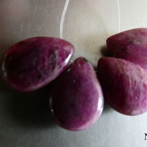 May include: Four teardrop-shaped purple gemstone beads with a smooth, polished finish.