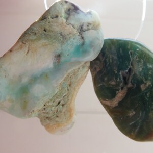 May include: Two irregularly shaped, polished stones. One is a light blue and green stone with white streaks. The other is a dark green stone with brown streaks. No. 2