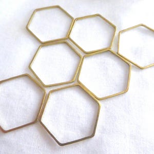 Peut inclure: Un ensemble de six hexagones en laiton &agrave; cadre ouvert dispos&eacute;s en grappe. Chaque pi&egrave;ce individuelle est une forme g&eacute;om&eacute;trique fine &agrave; six c&ocirc;t&eacute;s en m&eacute;tal avec une finition polie et lisse, cr&eacute;ant un motif en nid d'abeille sur la composition.
