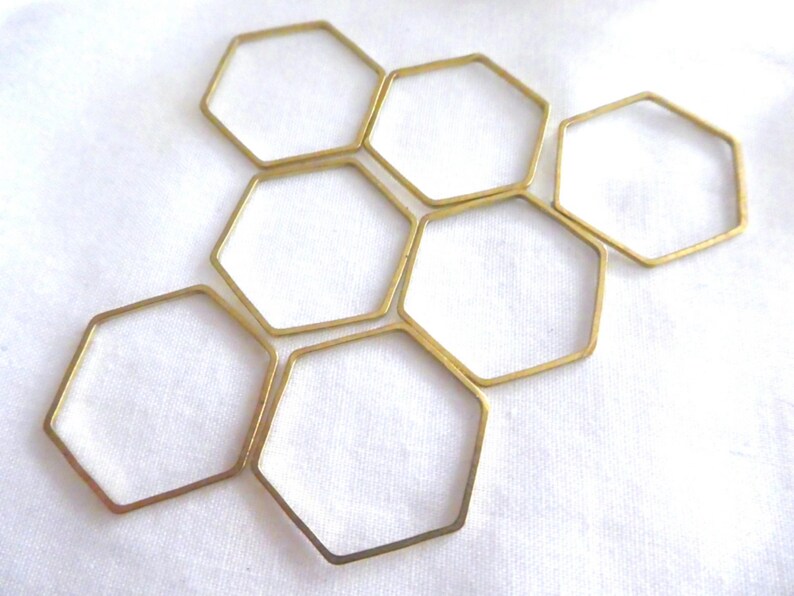 Peut inclure: Un ensemble de six hexagones en laiton &agrave; cadre ouvert dispos&eacute;s en grappe. Chaque pi&egrave;ce individuelle est une forme g&eacute;om&eacute;trique fine &agrave; six c&ocirc;t&eacute;s en m&eacute;tal avec une finition polie et lisse, cr&eacute;ant un motif en nid d'abeille sur la composition.
