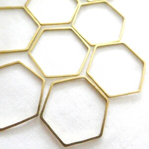 Peut inclure: Un ensemble de six hexagones en m&eacute;tal dor&eacute; &agrave; cadre ouvert dispos&eacute;s en motif de nid d'abeille. Chaque forme g&eacute;om&eacute;trique pr&eacute;sente des bords fins et lisses ainsi qu'une finition m&eacute;tallique, cr&eacute;ant une structure hexagonale r&eacute;p&eacute;titive.