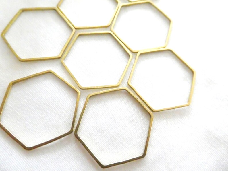 Peut inclure: Un ensemble de six hexagones en m&eacute;tal dor&eacute; &agrave; cadre ouvert dispos&eacute;s en motif de nid d'abeille. Chaque forme g&eacute;om&eacute;trique pr&eacute;sente des bords fins et lisses ainsi qu'une finition m&eacute;tallique, cr&eacute;ant une structure hexagonale r&eacute;p&eacute;titive.