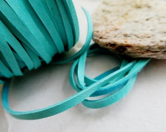 May include: Close-up of a roll of turquoise suede leather cord. The cord is unraveled in a loop, with a natural stone in the background. The cord is approximately 3mm wide, suitable for jewelry making and crafts.