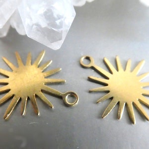 May include: Two gold-toned metal sunburst charms with a loop on each side. The charms are about 1 inch in diameter and have a starburst design with 16 points.