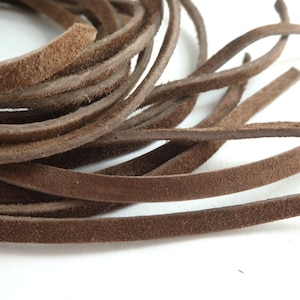 May include: A close-up of a bundle of brown leather cord. The cord is soft and supple, and it has a natural, rustic look.