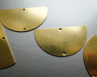 Peut inclure: Quatre formes en métal demi-cercle de couleur dorée avec deux trous chacune. Les formes sont disposées en quinconce sur une surface grise.