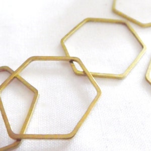 Peut inclure: Une collection de cadres hexagonaux en m&eacute;tal dor&eacute; fin dispos&eacute;s en un motif l&acirc;che et superpos&eacute;. Chaque cadre est une forme g&eacute;om&eacute;trique simple et ouverte avec une finition m&eacute;tallique lisse, cr&eacute;ant une s&eacute;rie de contours &agrave; six c&ocirc;t&eacute;s reli&eacute;s.