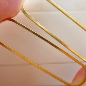 May include: A pair of gold oval-shaped earrings. The earrings are simple and minimalist in design.