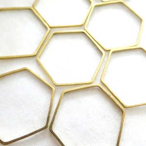 Peut inclure: Une collection de cadres m&eacute;talliques fins de couleur dor&eacute;e en forme d'hexagones. Ces formes g&eacute;om&eacute;triques &agrave; six c&ocirc;t&eacute;s sont dispos&eacute;es en grappe, avec une finition m&eacute;tallique lisse et des centres ouverts, cr&eacute;ant un motif r&eacute;p&eacute;titif de contours hexagonaux.
