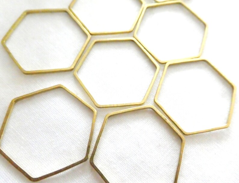 Peut inclure: Une collection de cadres m&eacute;talliques fins de couleur dor&eacute;e en forme d'hexagones. Ces formes g&eacute;om&eacute;triques &agrave; six c&ocirc;t&eacute;s sont dispos&eacute;es en grappe, avec une finition m&eacute;tallique lisse et des centres ouverts, cr&eacute;ant un motif r&eacute;p&eacute;titif de contours hexagonaux.