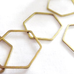 Peut inclure: Une collection de cadres hexagonaux en m&eacute;tal dor&eacute; fin, dispos&eacute;s en un motif l&acirc;che et superpos&eacute;. Chaque cadre est une forme g&eacute;om&eacute;trique simple et ouverte avec une finition m&eacute;tallique lisse, cr&eacute;ant une s&eacute;rie de contours hexagonaux reli&eacute;s.