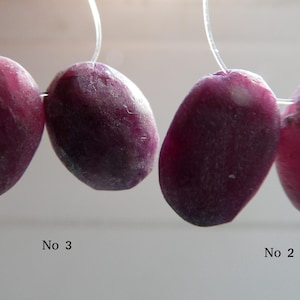 May include: Four oval-shaped, deep red gemstones strung on a thin, clear wire. The stones vary slightly in color and texture, with some appearing more translucent than others. The image includes the text "No 3" and "No 2".