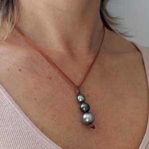 May include: A brown leather cord necklace with three dark green pearls.