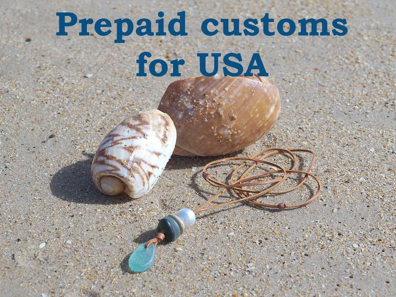May include: A necklace featuring a brown leather cord with a light blue sea glass pendant, a dark grey bead, and a white pearl bead, accompanied by two seashells. The text "Prepaid customs for USA" is displayed in blue at the top of the image.