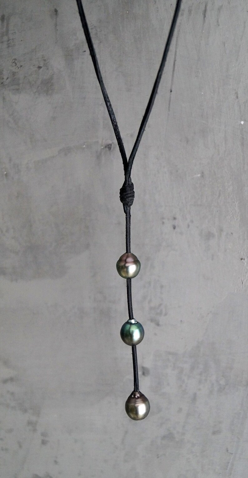 May include: A black leather cord necklace with three iridescent green pearls.