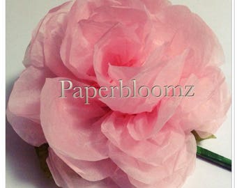 May include: A large, pink tissue paper flower with a layered, ruffled design. The flower is made of multiple layers of tissue paper, creating a full and voluminous look. The flower is a delicate and elegant decoration.