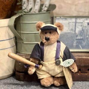 May include: A white ceramic mug with a black handle and the text "But First, Coffee" in a black, bold font. The mug is on a white surface. The mug is approximately 10 cm tall.