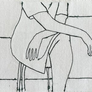 May include: Hand-stitched embroidery on white fabric depicts a seated figure. The figure's form is outlined in black thread, with details of arms, hands, and legs. The piece has a minimalist aesthetic, with horizontal lines suggesting a background.