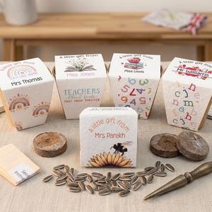 May include: A selection of small gift boxes with seed packets, seed starting discs, and sunflower seeds. The boxes are labelled "A little gift from" with names such as Mrs Thomas, Miss Jones, Miss Lewis, Mr Williams, and Mrs Parekh. The boxes feature various designs.