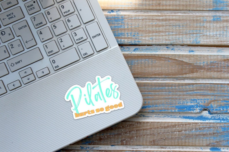 white and teal Pilates sticker that says Pilates hurts so good in a script font 3 x 3 inches