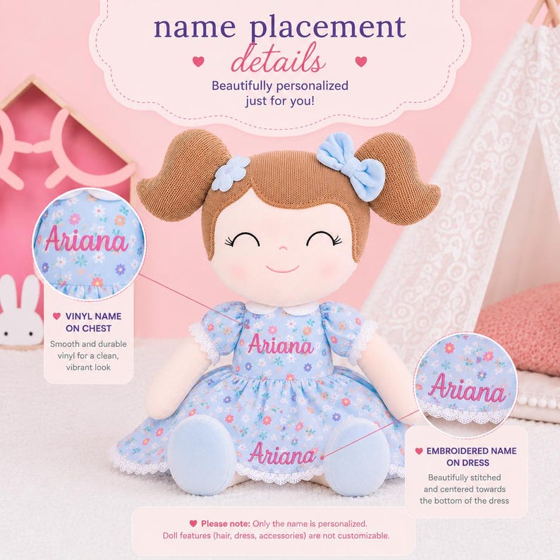 May include: A plush doll with brown hair in pigtails, wearing a light blue floral dress with white lace trim. The name Ariana is printed on the chest and embroidered on the dress hem. Text includes name placement details, vinyl name on chest, and embroidered name on dress.