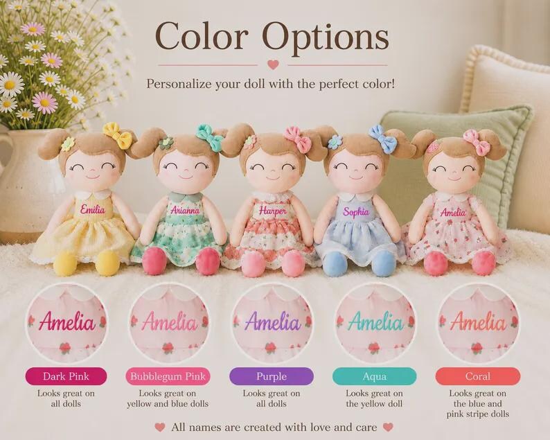 May include: Five personalized dolls with different colored dresses and bows. Each doll has a name embroidered on the dress. The image includes color options: Dark Pink, Bubblegum Pink, Purple, Aqua, and Coral. Text reads: "Color Options. Personalize your doll with the perfect color!"