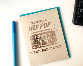 May include: A brown card with a teal border. The card has a gold foil design of a boombox with the text "You're a Hip Pop & You Don't Stop".