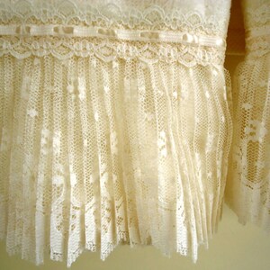 May include: A pair of white lace trim ruffles. The lace is delicate and has a scalloped edge.