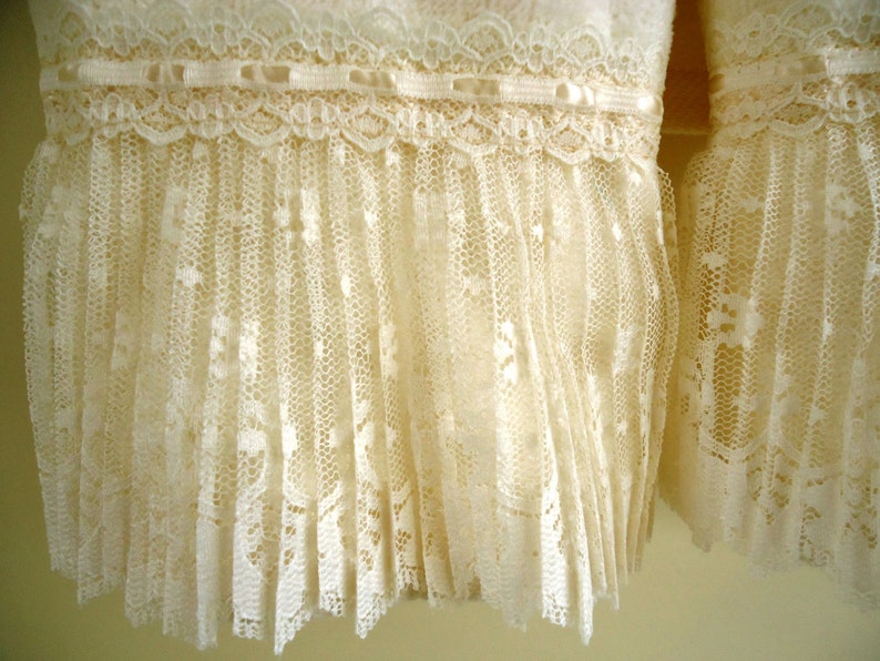 May include: A pair of white lace trim ruffles. The lace is delicate and has a scalloped edge.