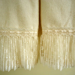 May include: Two white towels with a lace trim. The lace is a delicate, off-white color and has a ruffled edge. The towels are soft and fluffy.