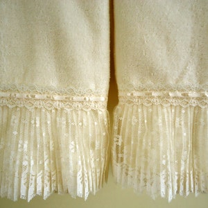May include: Two white towels with a lace trim. The towels are made of a soft, fluffy material and have a delicate lace trim around the bottom.