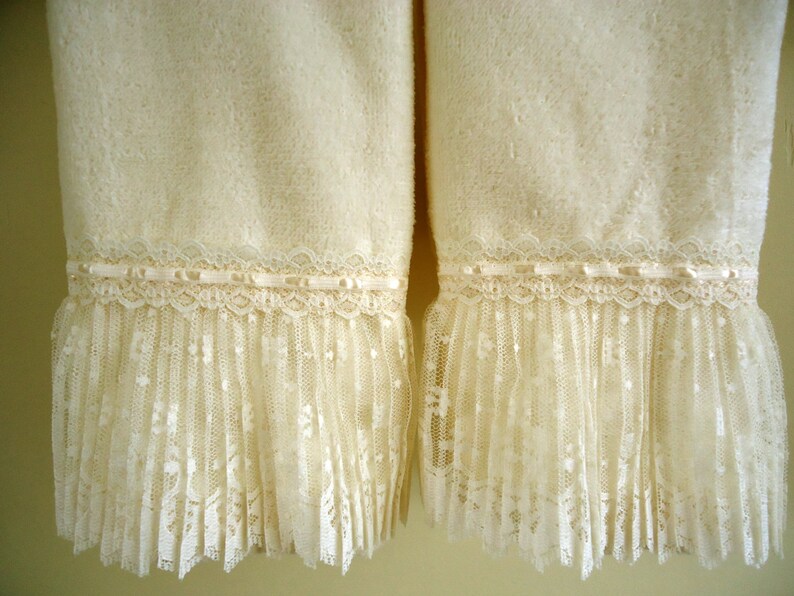 May include: Two white towels with a lace trim. The towels are made of a soft, fluffy material and have a delicate lace trim around the bottom.