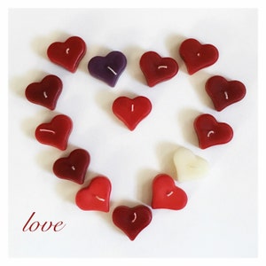 May include: A heart shape made of red, white, and purple heart-shaped candles. The word "love" is written in cursive at the bottom of the image.