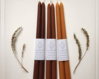 Może przedstawiać: Trzy zestawy po dwie brązowe i pomarańczowe świece z wosku pszczelego z białymi etykietami z napisem "Elizaaville Beeswax" i ilustracją pszczoły.