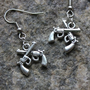 May include: A pair of silver earrings with a design of two crossed pistols.