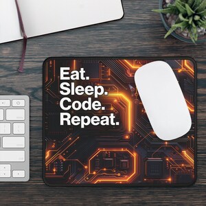 May include: A black mouse mat with an orange circuit board design and the text "Eat. Sleep. Code. Repeat."