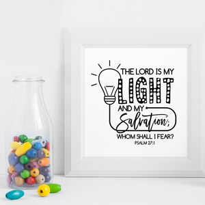 May include: A white framed print with black text that reads "The Lord is my Light and my Salvation: Whom shall I fear? Psalm 27:1". The text is stylized to look like a light bulb.