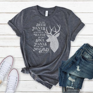 Könnte beinhalten: Ein graues T-Shirt mit einem weißen Hirsch-Motiv und dem Text "Wie der Hirsch nach dem Wasserstrom lechzt, so sehnt sich meine Seele nach dir, mein Gott." Psalm 42:1.