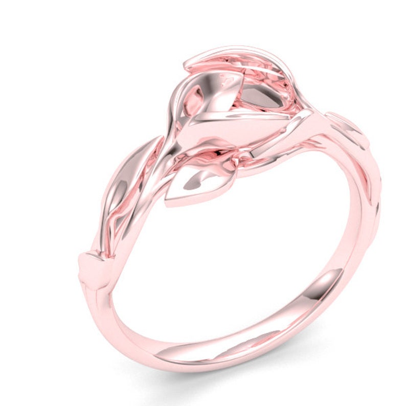 May include: A rose gold ring with a delicate floral design. The ring features a stylized rose bud with leaves wrapping around the band.