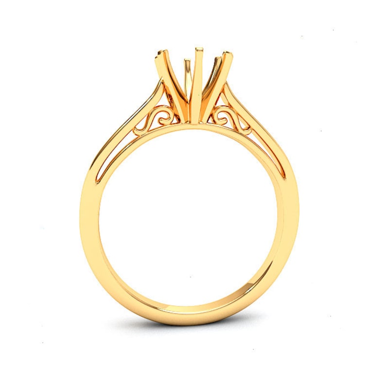 May include: A gold ring with a delicate, ornate design. The ring has a center setting for a stone, and the band is thin and delicate.