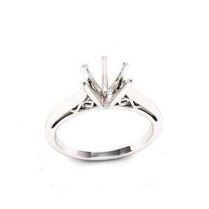 May include: A silver ring setting with a delicate, ornate design. The setting is designed to hold a large, round gemstone.