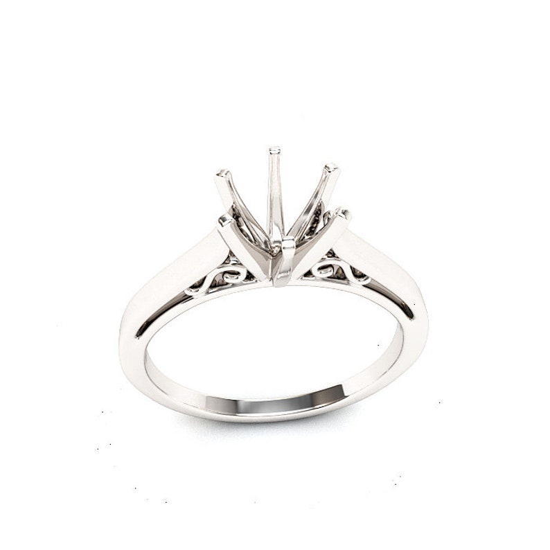 May include: A silver ring setting with a delicate, ornate design. The setting is designed to hold a large, round gemstone.