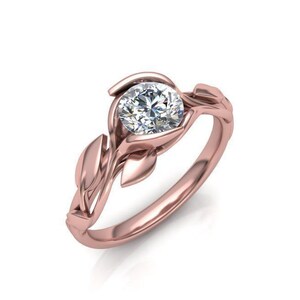 May include: A rose gold engagement ring with a round diamond set in a delicate floral design.